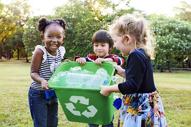 crianças segurando um cesto de reciclagem de garrafas pet