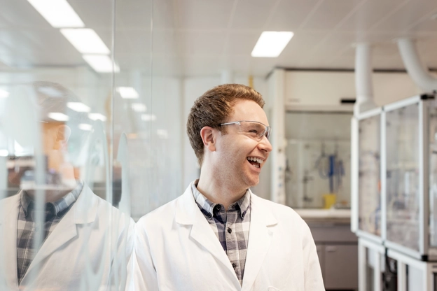 Homem em uma laboratório, sorrindo. GSK