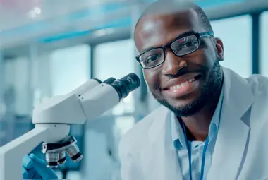 Colaborador posando para foto ao lado de um equipamento científico