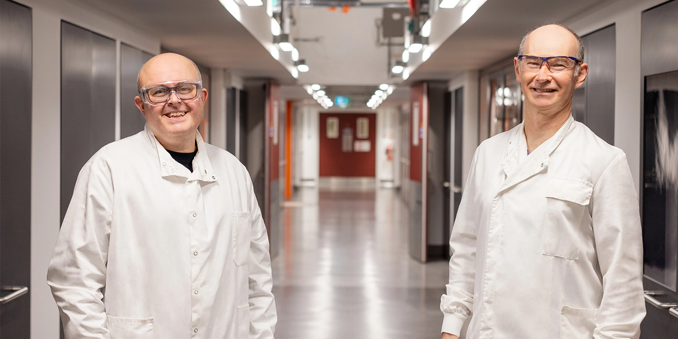 Dois cientistas sorrindo em um corredor, educação médica independente.