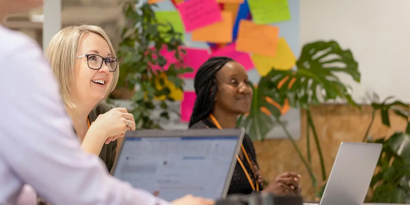 Colaboradores sorrindo em uma reunião, GSK em foco